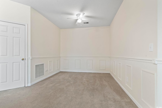 empty room with a ceiling fan, carpet, visible vents, and a decorative wall