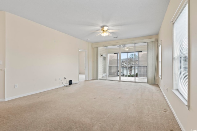 carpeted spare room featuring ceiling fan, visible vents, and baseboards