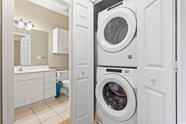 laundry area with laundry area, light tile patterned floors, a sink, and stacked washer and clothes dryer