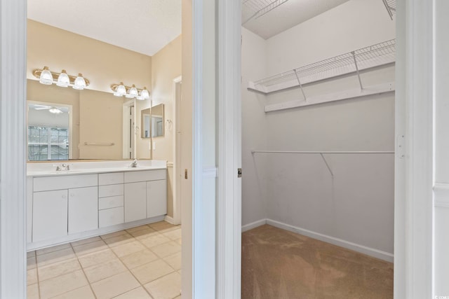 full bath with double vanity, a sink, and a walk in closet