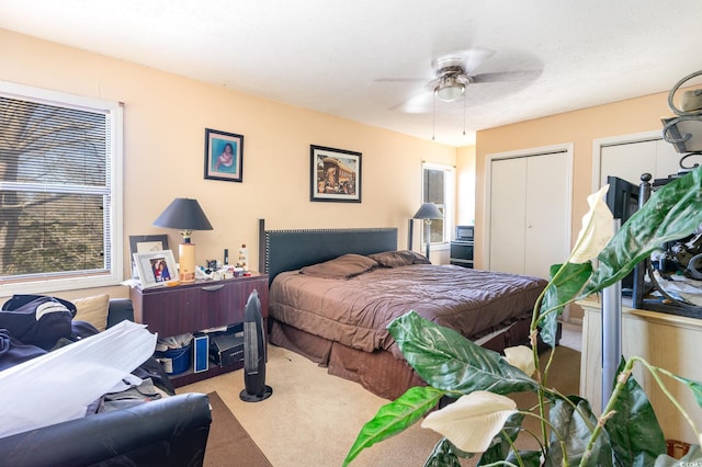 bedroom featuring ceiling fan, two closets, and carpet