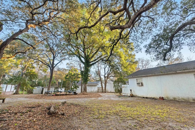 view of yard with cooling unit, a storage shed, and a trampoline