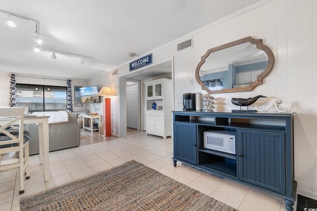 kitchen featuring light tile patterned floors, blue cabinets, wood walls, and a textured ceiling