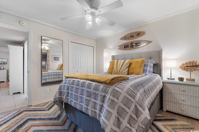 bedroom featuring ceiling fan, a textured ceiling, a closet, and ornamental molding