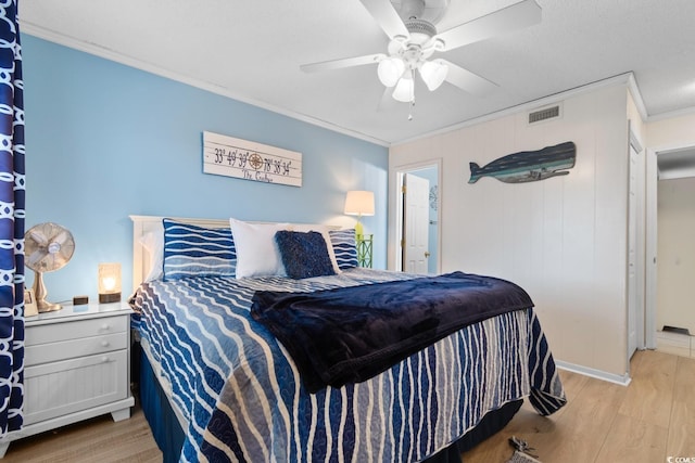 bedroom featuring light wood-type flooring, ceiling fan, and crown molding