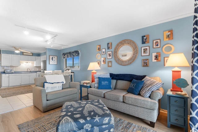 living room with ceiling fan, sink, light wood-type flooring, ornamental molding, and rail lighting