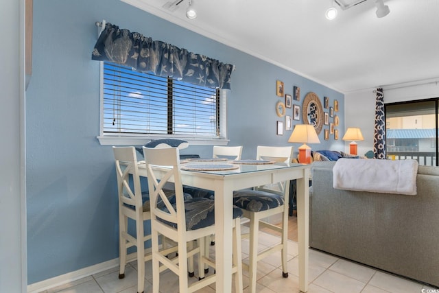 dining space featuring light tile patterned floors, crown molding, and track lighting