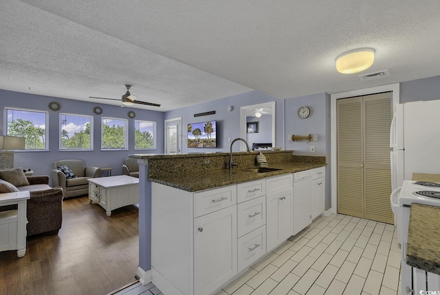 kitchen with sink, dark stone countertops, white cabinets, kitchen peninsula, and white appliances