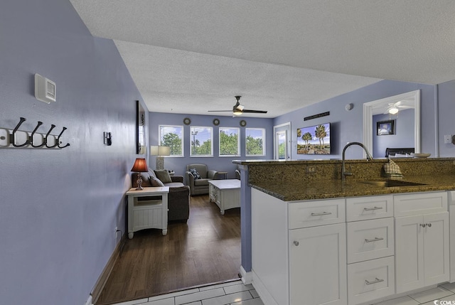 kitchen with white cabinetry, sink, dark stone countertops, tile patterned flooring, and ceiling fan