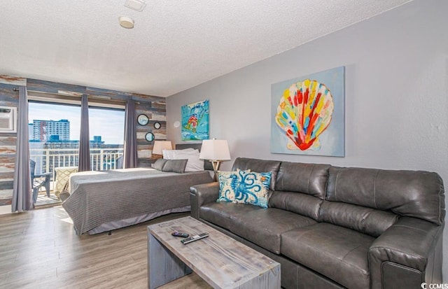 bedroom featuring access to exterior, a textured ceiling, and light hardwood / wood-style floors