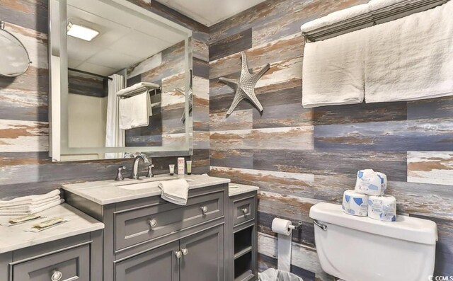 bathroom with toilet, vanity, and wooden walls