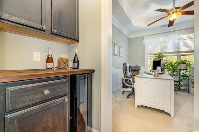 home office featuring wine cooler, ornamental molding, light colored carpet, bar area, and a tray ceiling