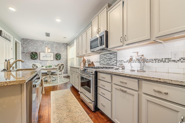 kitchen featuring light stone countertops, appliances with stainless steel finishes, dark hardwood / wood-style floors, and decorative light fixtures