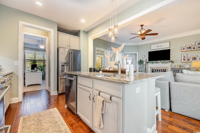 kitchen featuring white cabinets, decorative light fixtures, sink, stainless steel dishwasher, and a center island with sink