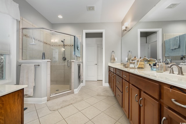 bathroom with a shower with shower door, vanity, and tile patterned floors