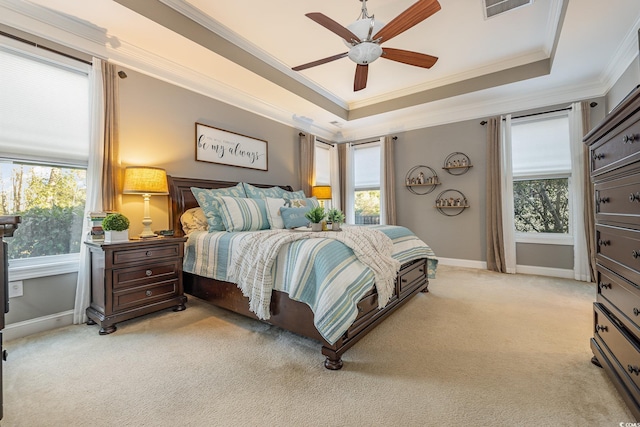 bedroom featuring light carpet, ceiling fan, crown molding, and a tray ceiling