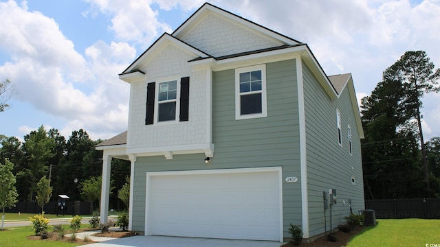 view of front of property featuring cooling unit, a garage, and a front lawn