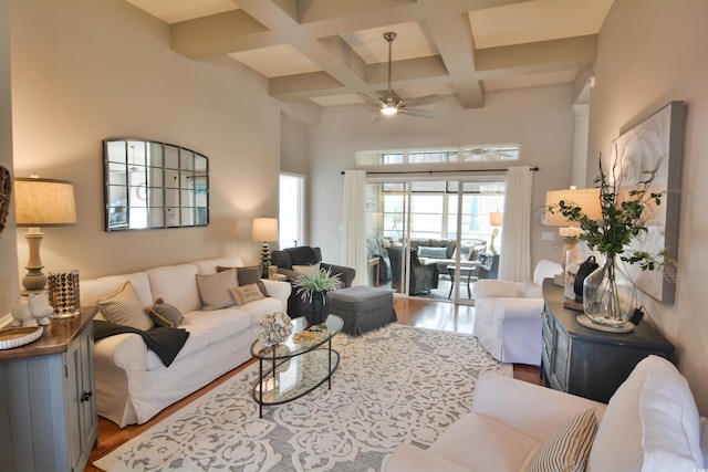 living room with hardwood / wood-style flooring, ceiling fan, a towering ceiling, coffered ceiling, and beamed ceiling