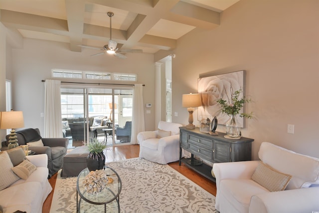 living room featuring ceiling fan, coffered ceiling, light hardwood / wood-style floors, and beam ceiling