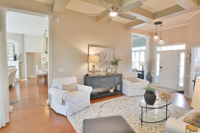 living room with coffered ceiling, beam ceiling, light hardwood / wood-style floors, and ornate columns