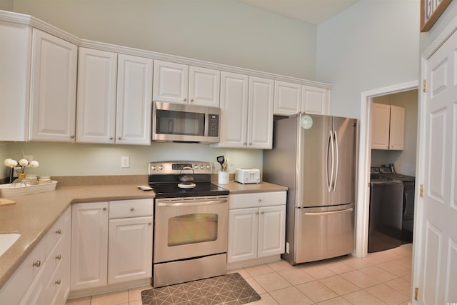 kitchen featuring white cabinetry, stainless steel appliances, washer and clothes dryer, and light tile patterned floors