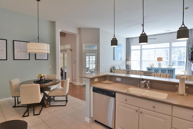 kitchen with light tile patterned floors, sink, dishwasher, hanging light fixtures, and white cabinets