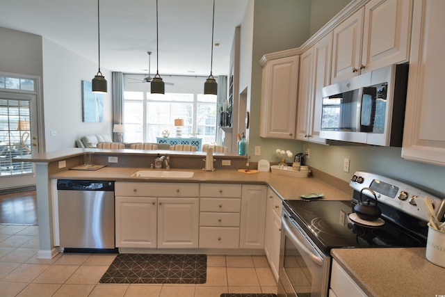 kitchen featuring sink, light tile patterned floors, appliances with stainless steel finishes, kitchen peninsula, and pendant lighting