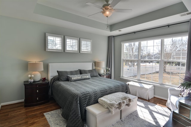 bedroom with dark hardwood / wood-style flooring, a raised ceiling, and ceiling fan