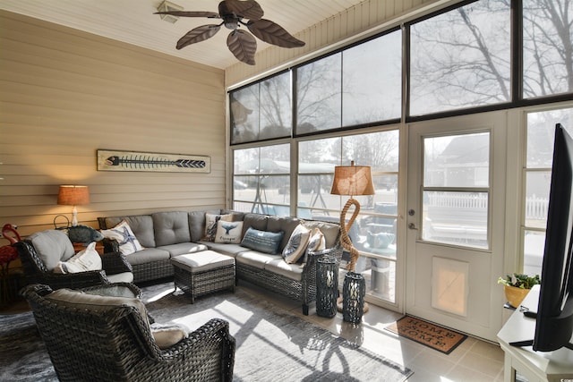 tiled living room with ceiling fan and wooden walls