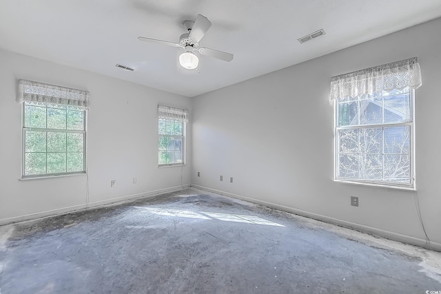 empty room featuring ceiling fan, concrete flooring, and plenty of natural light