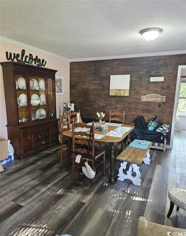 dining area featuring a textured ceiling, ornamental molding, and wood finished floors