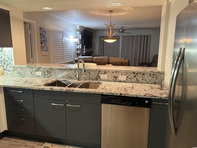 kitchen with sink, stainless steel appliances, a textured ceiling, and light stone countertops