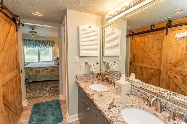 bathroom featuring vanity, hardwood / wood-style floors, ceiling fan, and a textured ceiling