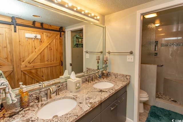 bathroom featuring vanity, an enclosed shower, a textured ceiling, and toilet