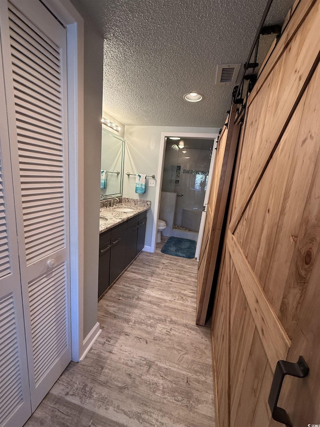 bathroom with toilet, a textured ceiling, vanity, a shower with door, and hardwood / wood-style flooring