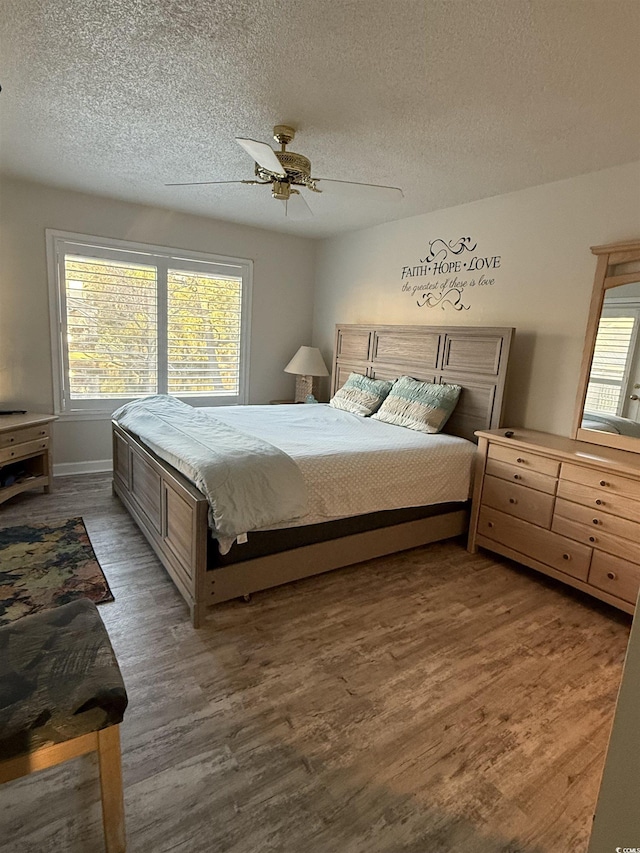 bedroom with multiple windows, a textured ceiling, dark wood-type flooring, and ceiling fan