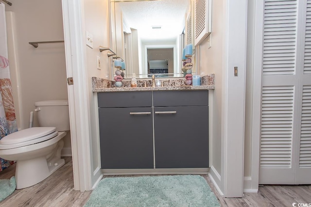 bathroom with vanity, hardwood / wood-style floors, a textured ceiling, and toilet