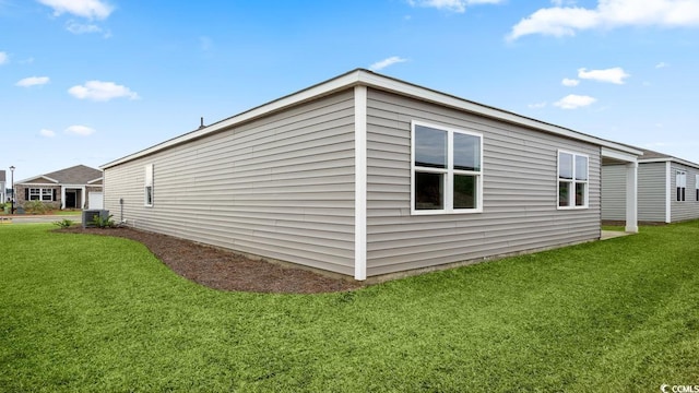 view of side of property featuring a yard and central AC