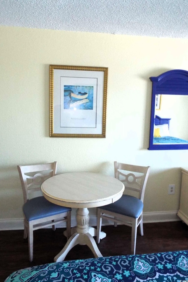 dining room with a textured ceiling, dark wood-type flooring, and baseboards