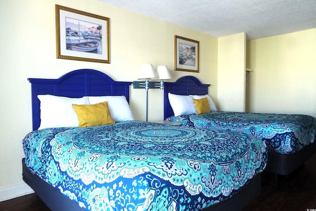 bedroom featuring a textured ceiling, wood finished floors, and baseboards