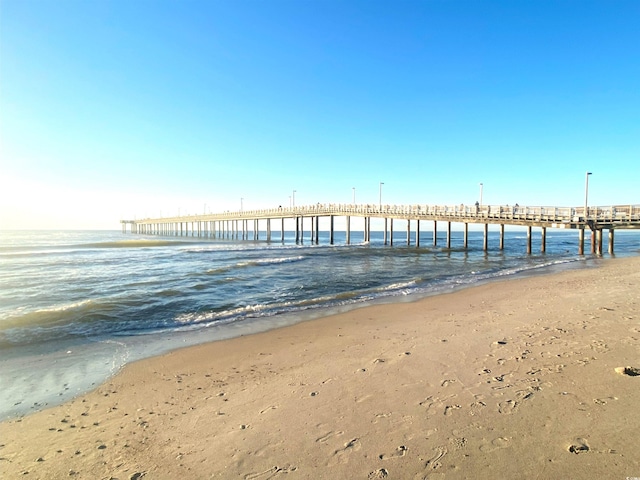 dock area with a pier, a beach view, and a water view