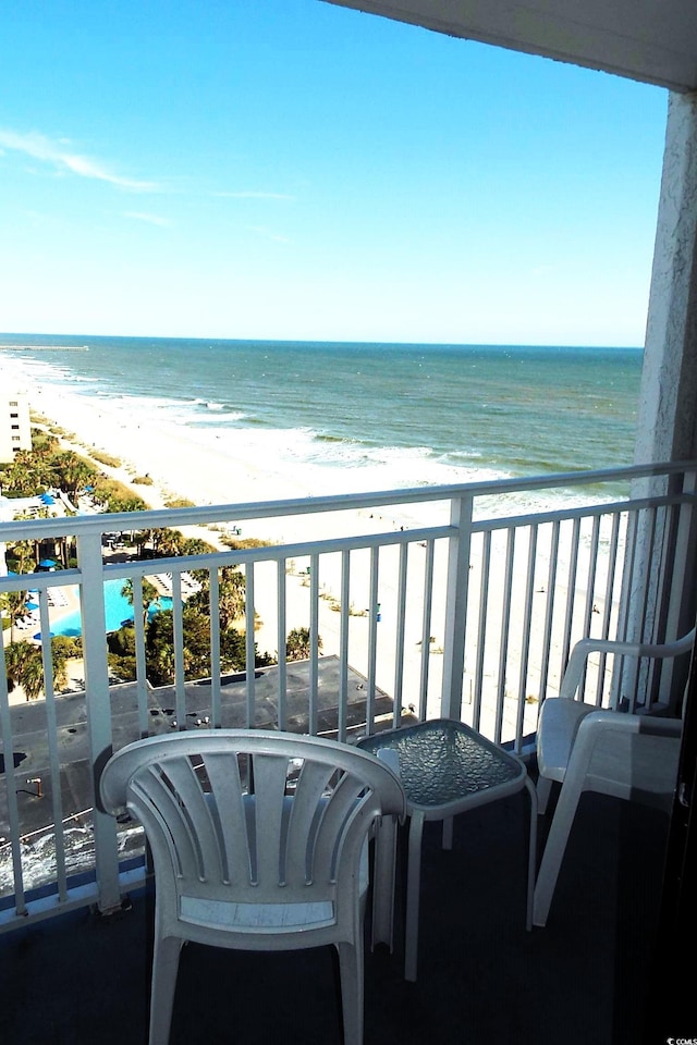 balcony with a water view and a view of the beach