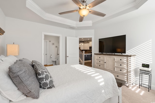 carpeted bedroom featuring a raised ceiling, ornamental molding, ceiling fan, and ensuite bath