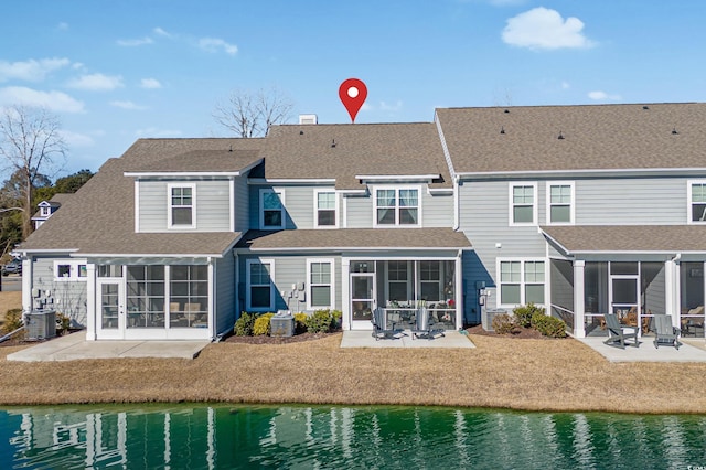 back of property with a water view, a patio area, and a sunroom