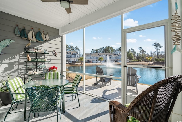 sunroom / solarium with a water view and ceiling fan