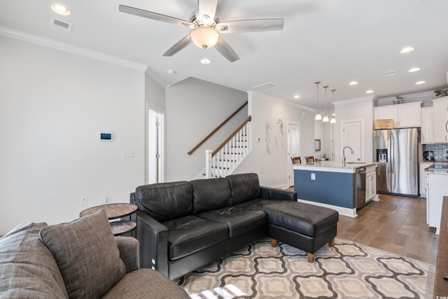 living room featuring sink, crown molding, light hardwood / wood-style floors, and ceiling fan