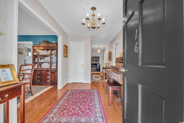 entrance foyer featuring a chandelier, light wood-type flooring, and a fireplace