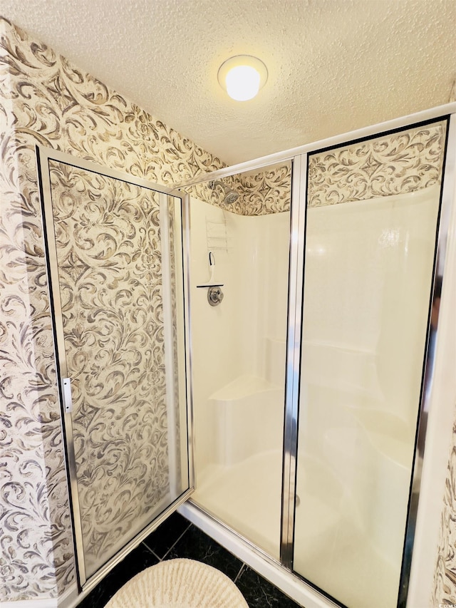 bathroom featuring a shower with shower door, a textured ceiling, and tile patterned flooring