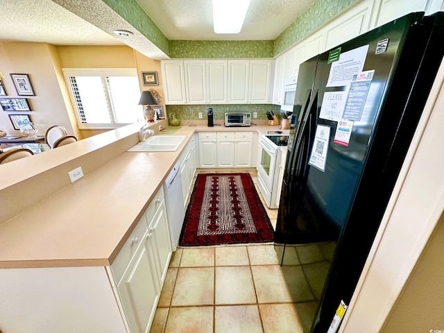 kitchen with light tile patterned flooring, sink, white appliances, white cabinetry, and a textured ceiling