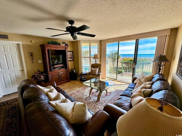 living room featuring ceiling fan, a textured ceiling, and light tile patterned floors